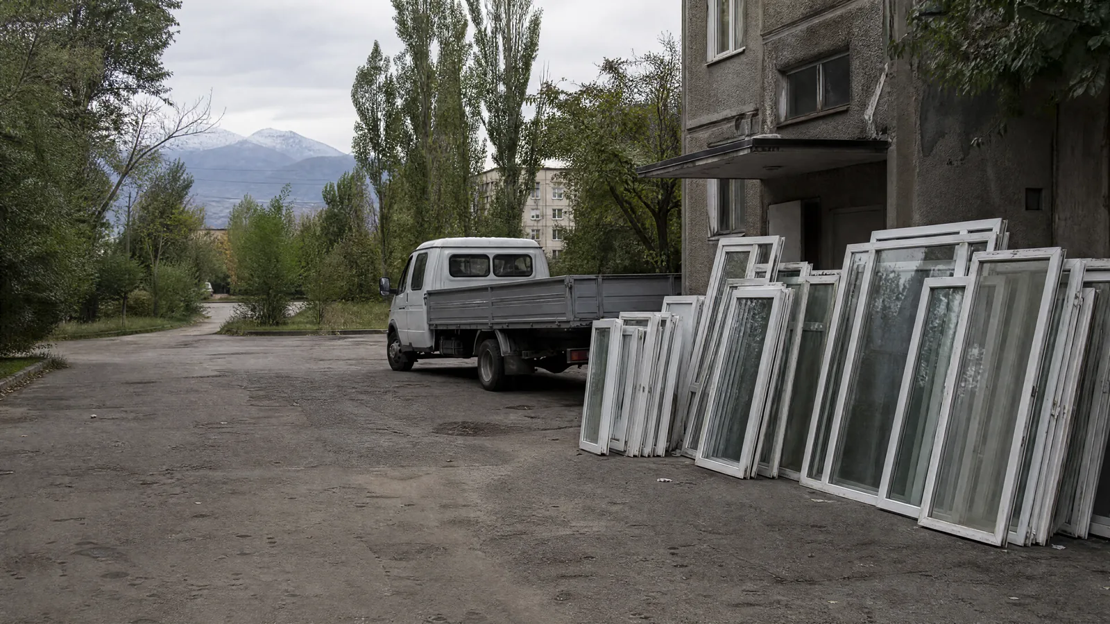 Old plastic frames and double-glazed units by the wall of the entrance before loading into a GAZelle