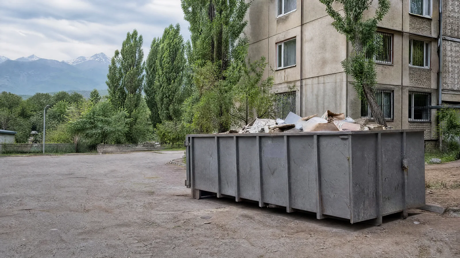 Бункер-контейнер 8 м³ с строительным мусором во дворе дома в Алматы