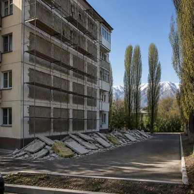 Фасад здания до демонтажа панелей: леса, строительный мусор внизу