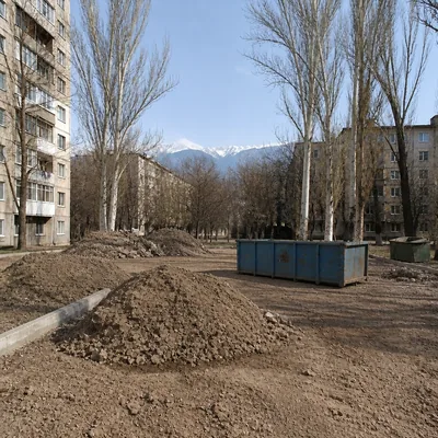 Захламлённый двор, кучи земли и грунта по краям
