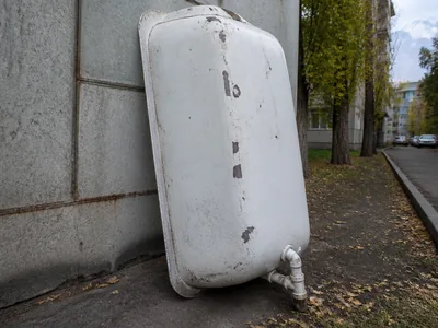 Старая стальная ванна у стены